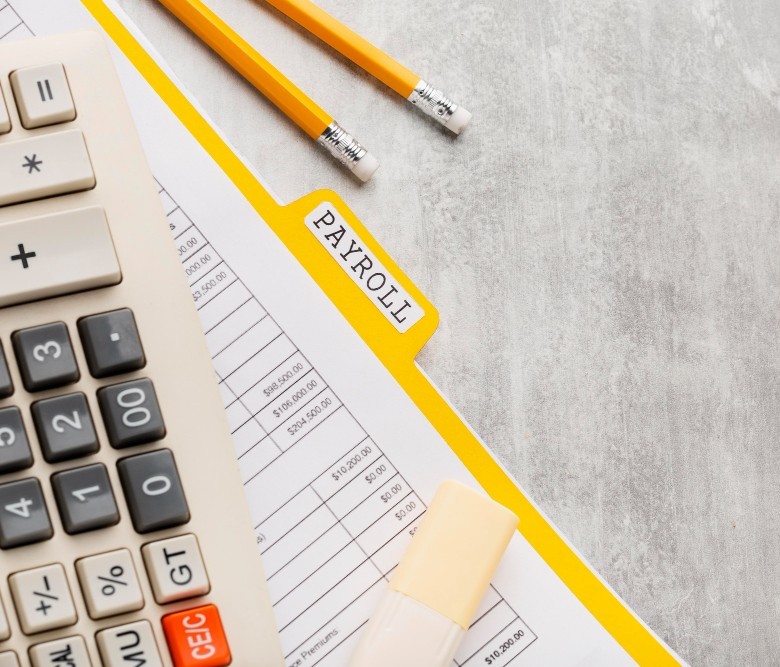 A paper folder titled "Payroll" lying on a desk